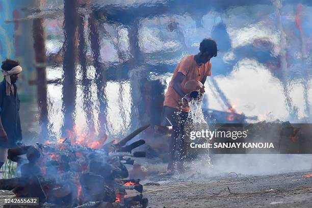 People cremate on open-air pyres along a street in Allahabad on August 22, 2022.