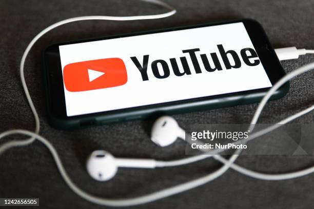 YouTube logo displayed on a phone and headphones are seen in this illustration photo taken in Krakow, Poland on August 22, 2022.