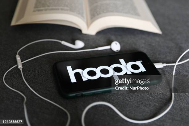 Hoopla logo displayed on a phone, headphones and a book are seen in this illustration photo taken in Krakow, Poland on August 22, 2022.