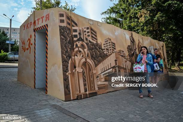 Members of the public stand beside a newly constructed bomb shelter, built to protect civilians from shelling, near a bus stop in Kharkiv, on August...