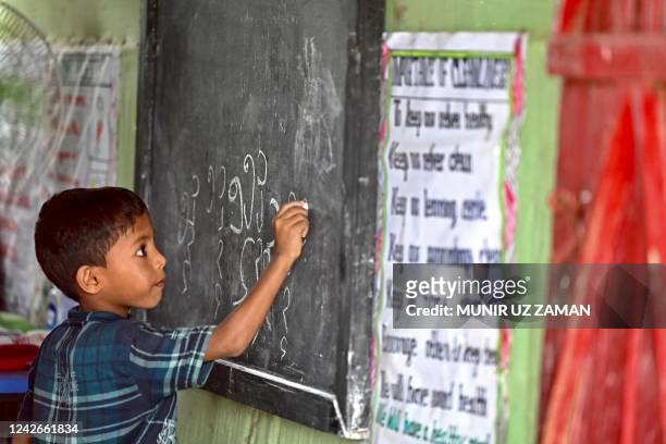 In this picture taken on August 10 a Rohingya refugee child writes Rohingya language on a blackboard at a school in Kutupalong refugee camp in Ukhia....