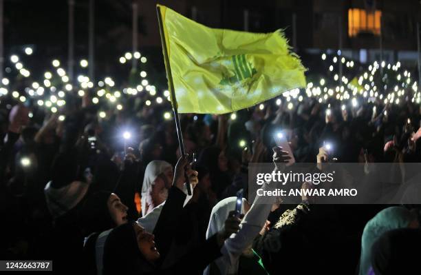 Supporters of Hezbollah hold up their phones and wave the party flag during a celebration marking the 40th anniversary of the Shiite movement...