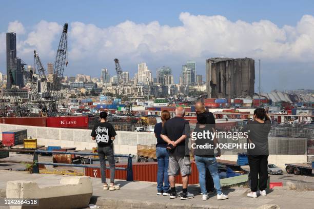 People standing outside the port of Lebanon's capital Beirut look at the newly-collapsed northern section of the grain silos, which were previously...
