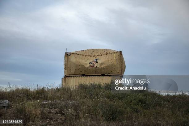 The wreckage of containers is seen holed by the shrapnel of an explosion as they lay on the field of the shooting range area nearby the Tofta...