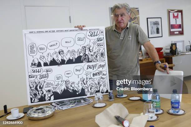 Nick Hayek, chief executive officer of Swatch Group AG, displays a comic board parody of a trading floor during an interview at the company's...