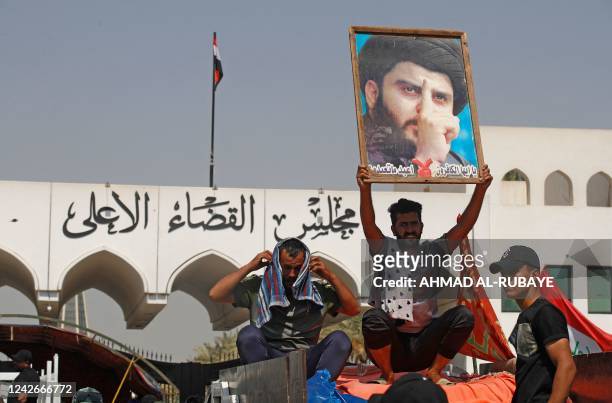 Supporter of Iraqi Muslim Shiite cleric Moqtada Sadr raises his portrait during a protest outside the headquarters of the Supreme Judicial Council,...