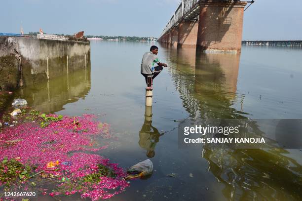 An angler sits on a hand pump in a flooded area on the banks of the Ganges River in Allahabad on August 23 as water levels rose following monsoon...