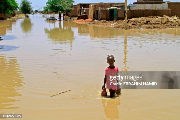 Girl wades through flood water in Managil city in al-Gezira state, around 250Km south of the capital, on August 23, 2022. - Sudan declared a state of...