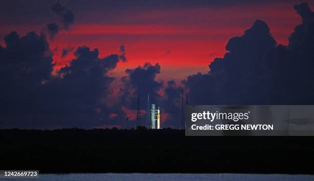 The sky begins to clear before dawn, highlighting the Artemis-1 moon rocket at Launch Pad 39 at the Kennedy Space Center, in this view from...