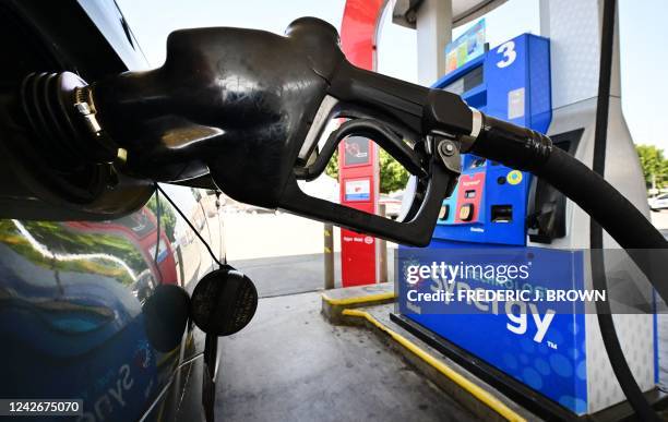 Gasoline nozzle pumps gas into a vehicle in Los Angeles, California on August 23, 2022. - US shoppers are facing increasingly high prices on everyday...