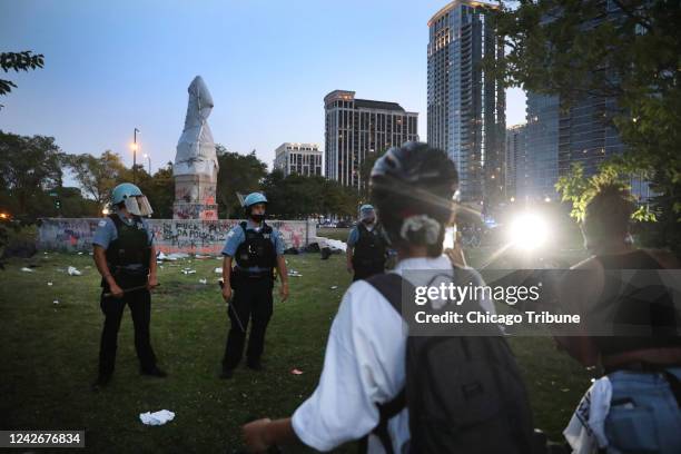 Protesters argue with Chicago police after trying to topple the Christopher Columbus statue in Grant Park during a rally calling for the defunding of...