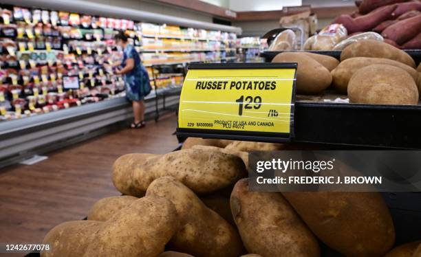 Shopper is seen past a sign displaying the price per pound of russet potatoes at a supermarket in Montebello, California, on August 23, 2022. - US...