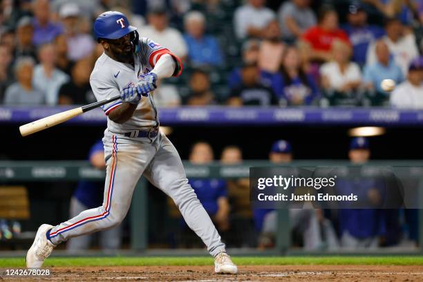 Adolis Garcia of the Texas Rangers hits an RBI single before advancing to second base in the fifth inning against the Colorado Rockies at Coors Field...