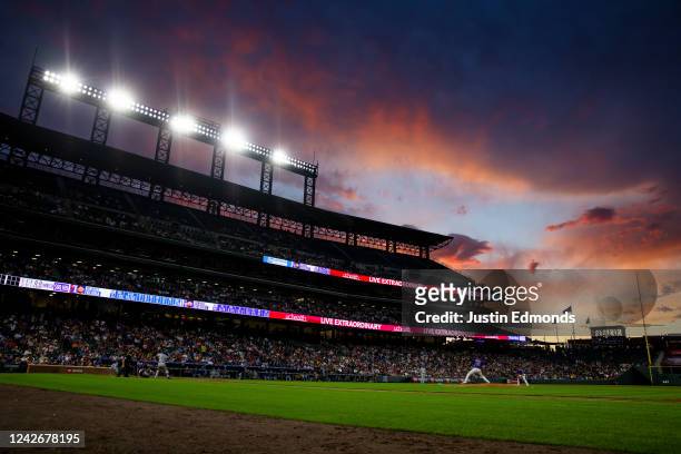 German Marquez of the Colorado Rockies delivers a pitch to home plate against Meibrys Viloria of the Texas Rangers as the sun sets behind the stadium...