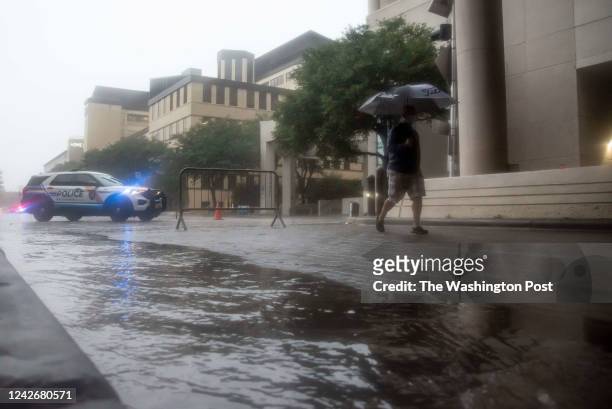 Pedestrian walks through the heavy rain with an umbrella near Baylor Scott & White Hospital on Hall Street in Dallas, Texas on Monday, August 22,...