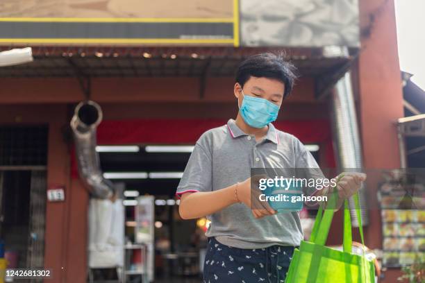 teenage boy buying takeout food from a restaurant using reusable food container - reusable stock pictures, royalty-free photos & images