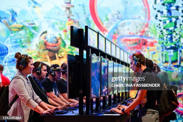 Visitors play the game 'Park Beyond', a video game published by Bandai Namco Entertainment, at the Gamescom video game fair in Cologne, western...