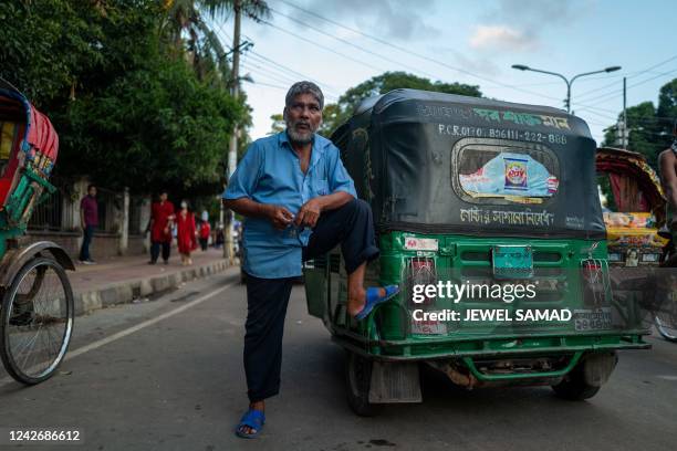 An auto-rickshaw driver waits for passengers along a street in Dhaka on August 24, 2022.