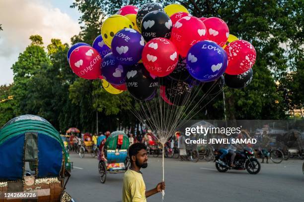 Vendor selling balloons waits for customers along a street in Dhaka on August 24, 2022.