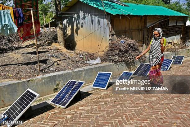 Rohingya refugee woman walks past the solar panels along a street at a Hindu Rohingya camp in Ukhia on August 24, 2022.