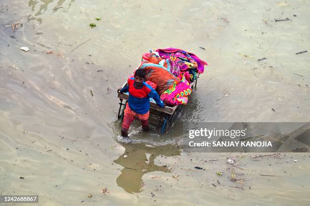 Flood-affected resident of a low lying area moves his belongings on a handcart to a safer place on the banks of river Ganges following heavy monsoon...