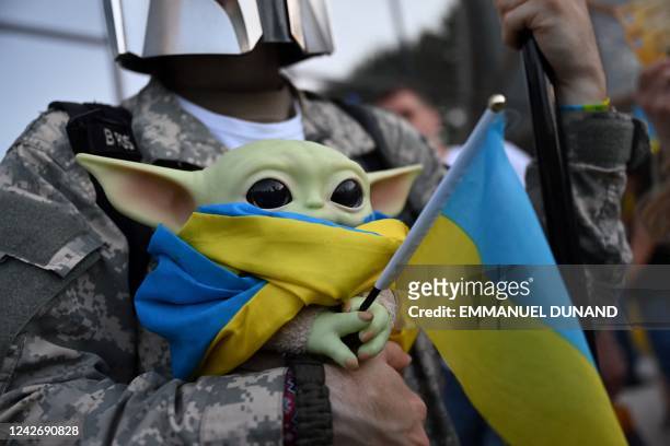 Demonstrator holds a Grogu / Baby Yoda figurine, a character from the Star Wars Disney+ original television series The Mandalorian, wrapped in a...
