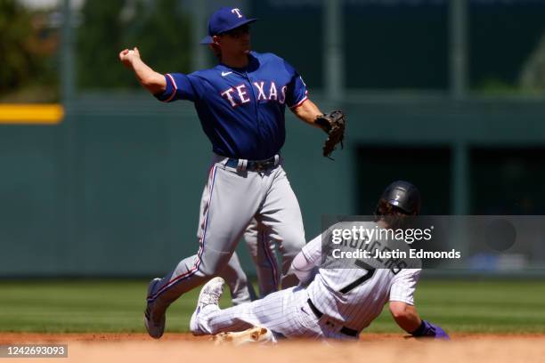 Shortstop Corey Seager of the Texas Rangers throws to first base to complete the double play as Brendan Rodgers of the Colorado Rockies slides in...