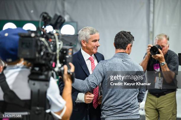Commissioner Jay Monahan smiles as he greets Rory McIlroy of Northern Ireland while a Netflix and Vox Media camera rolls at a press conference prior...