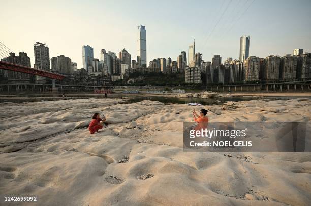 People are seen at the dried-up riverbed of the Jialing river, a tributary of the Yangtze River in China's southwestern city of Chongqing on August...