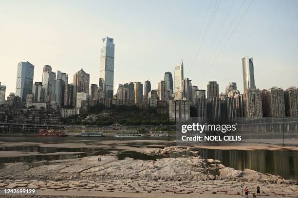 People are seen at the dried-up riverbed of the Jialing river, a tributary of the Yangtze River in China's southwestern city of Chongqing on August...