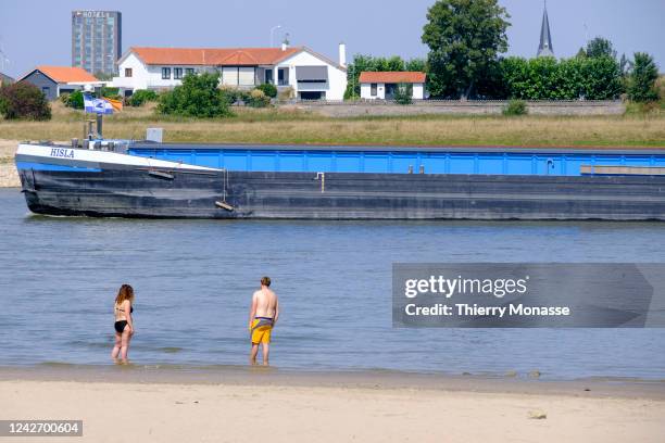 Couple enjoy the banks and the water while the Dutch flag barge Isla is sailing under the waalbrug in the Waal river, the main distributary branch of...