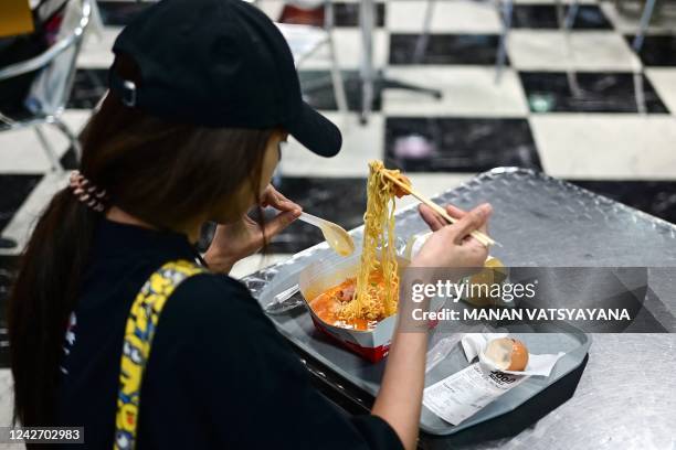 Woman eats Instant noodles for lunch at the Good Noodle store selling a wide variety of instant noodles from across Asia, in Bangkok on August 25,...