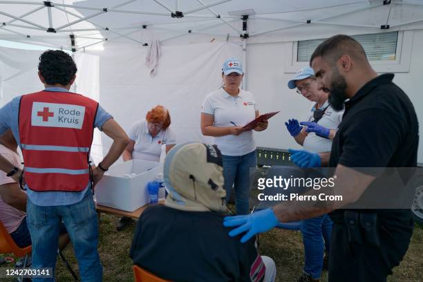 Medical staff of the Red Cross give medical care to refugees as hundreds of refugees sleep rough outside the refugee center on August 25, 2022 in Ter...
