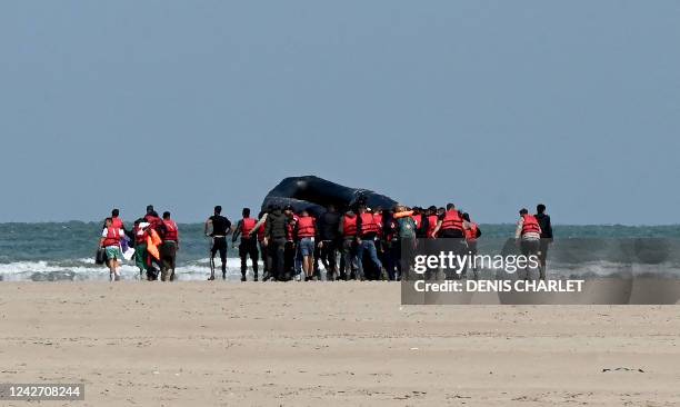 Migrants push an inflatable boat across a stretch of sand towards the water, near Gravelines, northern France, on August 25 before they attempt to...