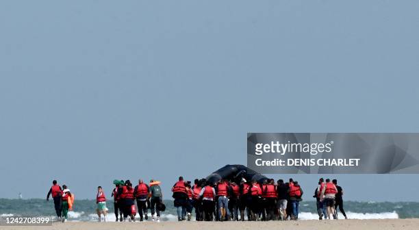 Migrants push an inflatable boat across a stretch of sand towards the water, near Gravelines, northern France, on August 25 before they attempt to...
