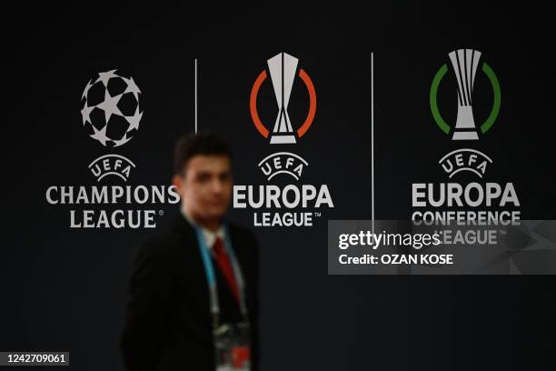 Man walks by the logos of the UEFA Champions League , the Europa League and the Europa Conference League prior to the draw ceremony for the UEFA...