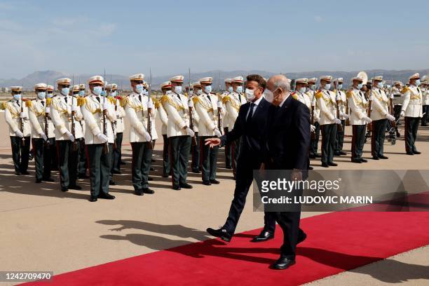 French President Emmanuel Macron and Algeria's President Abdelmadjid Tebboune review a guard of hounour at the airport in Algiers on August 25 at the...