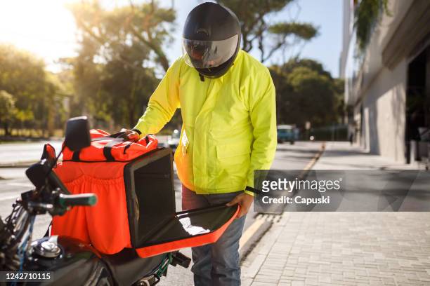 delivery biker open his delivery backpack - motoboy - motoboy stock pictures, royalty-free photos & images