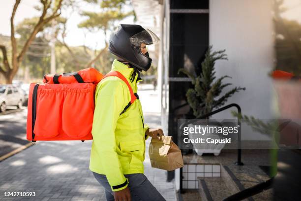 delivery man arriving on destination side view - motoboy - motoboy stock pictures, royalty-free photos & images