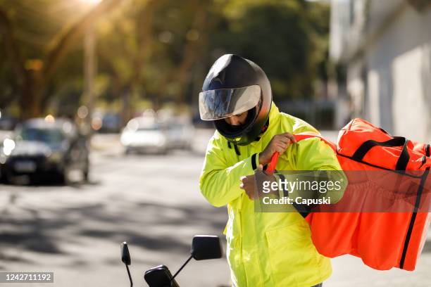delivery man removing his backpack - motoboy - motoboy stock pictures, royalty-free photos & images
