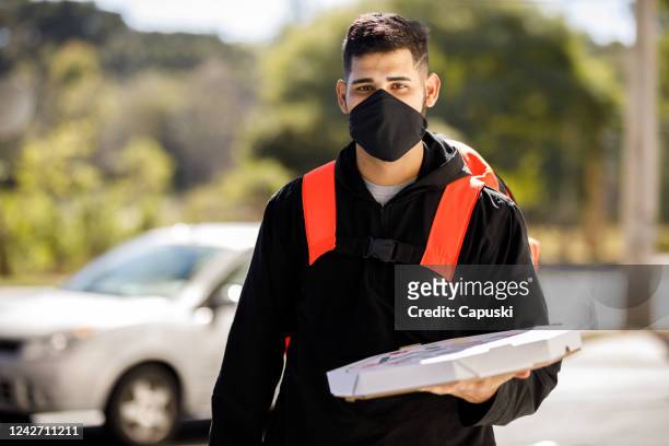 man delivering a pizza wearing mask - motoboy - motoboy stock pictures, royalty-free photos & images