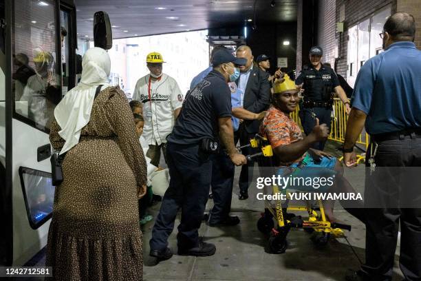 Migrant in a wheelchair, who boarded a bus in Texas, is assisted as they arrive at Port Authority Bus Terminal in New York City on August 25, 2022. -...