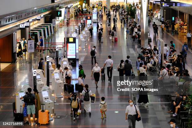 Passengers wearing face masks as a preventive measure against the spread of covid-19 are seen at the Tokyo International Airport, commonly known as...