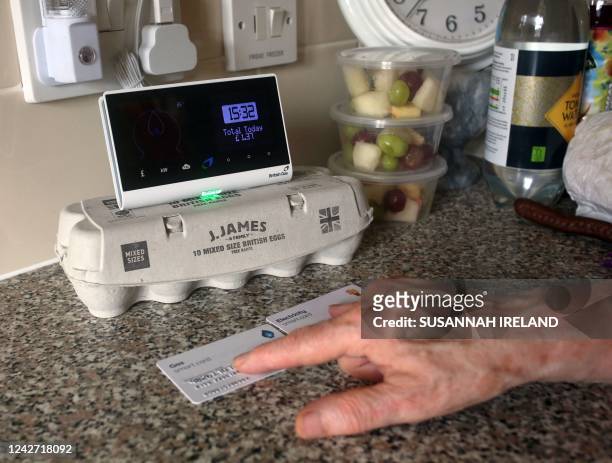 An energy customer examines the smart meter in her flat on the south London estate where she lives, on August 25, 2022. - Increasingly cash-strapped...