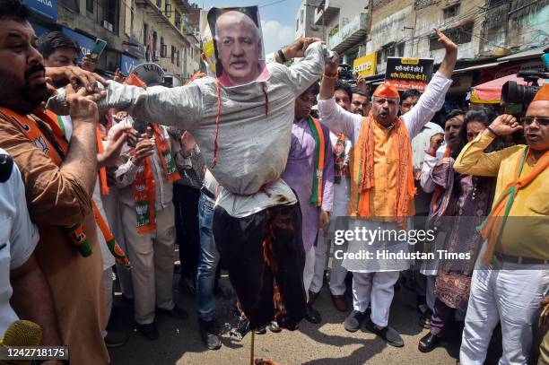 Delhi BJP President Adesh Gupta and other party workers burn an effigy of Delhi Deputy CM Manish Sisodia, during a protest demanding his resignation...