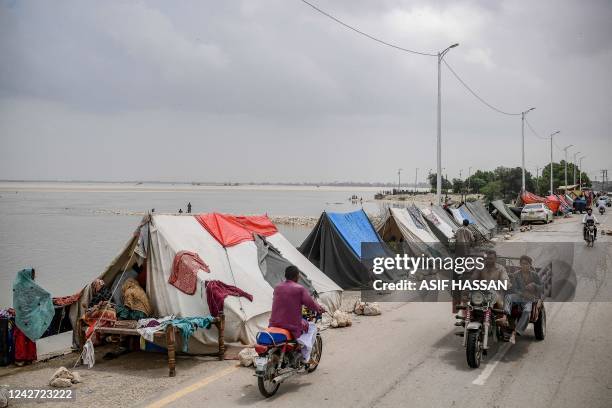 Motorists ride past temporary tents setup for displaced people who fled their flood hit homes following heavy monsoon rainfalls in Sukkur of Sindh...