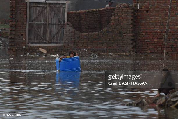 Man uses a plastic drum to cross a flooded area after heavy monsoon rains in Jacobabad, Sindh province, on August 26, 2022. - Heavy rain pounded much...
