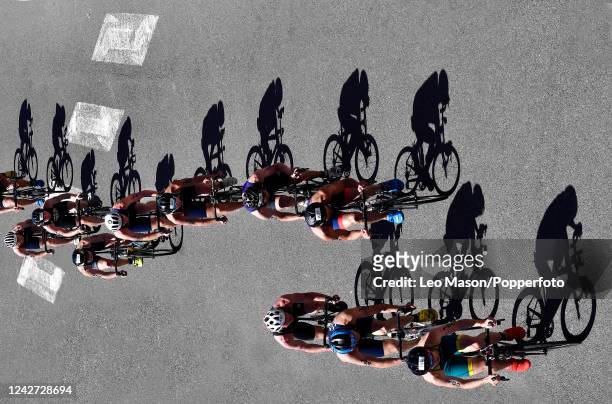 The photographer has chosen this image to displayed in this format to bring attention to the line of shadows. Athletes riding bicyles during the...
