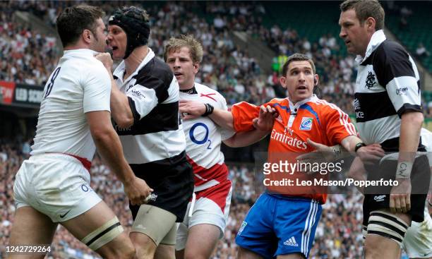 Barbarians' Australian player Stephen Larkham grabs England's Captain Nick Easter as teammates and referee look on, after Easter scored a try during...