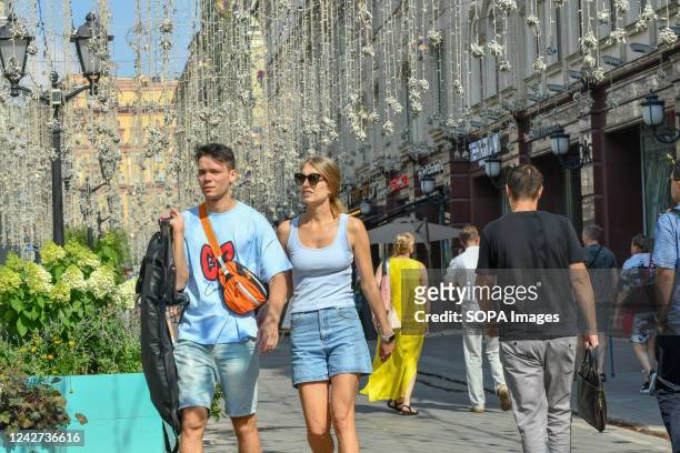 Couple walks along the Nikolskaya Street on a sunny day.